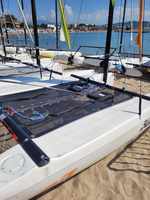Gros plan sur le transfilage rouge et bleu d'un trampoline de catamaran, bateau posé sur la plage